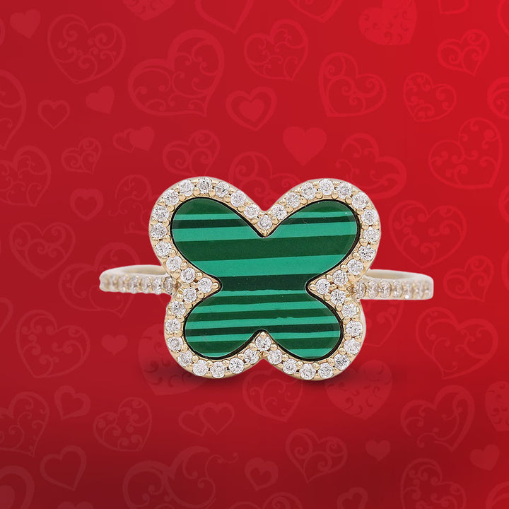 An emerald and diamond butterfly ring on a red background.