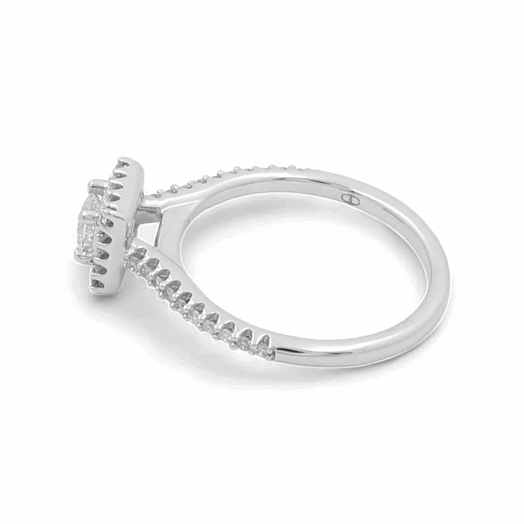 This exquisite 14K white gold bridal ring from Miral Jewelry features a prong-set central gemstone, elegantly accented with small diamonds lining the band.