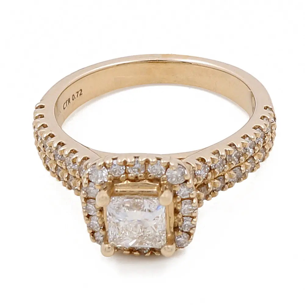 A 14K Yellow Gold Women's Contemporary Engagement Ring with 0.75Tw Round Diamonds by Miral Jewelry with a square center diamond surrounded by smaller round diamonds and additional diamonds along the band. The 0.72 CT diamond is inscribed on the inside of this contemporary engagement ring.