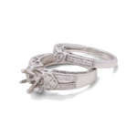 The 14K White Gold Bridal Woman Ring with Diamonds by Miral Jewelry is a beautifully crafted bridal ring set, featuring a silver engagement ring and wedding band adorned with intricate detailing and small embedded diamonds. The engagement ring is designed to hold a central gemstone.