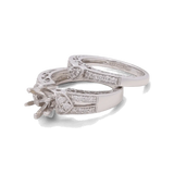 The 14K White Gold Bridal Woman Ring with Diamonds by Miral Jewelry is a beautifully crafted bridal ring set, featuring a silver engagement ring and wedding band adorned with intricate detailing and small embedded diamonds. The engagement ring is designed to hold a central gemstone.