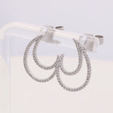 A pair of Miral Jewelry's 14K White Gold Fashion Diamond Women Earring Drops, adorned with small, sparkling clear stones, is displayed on a transparent stand, exuding the elegance of the Fashion Diamond collection.