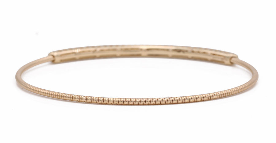 A Yellow Gold 14K Bangle Bracelet With Diamonds by Miral Jewelry with a thin wire.