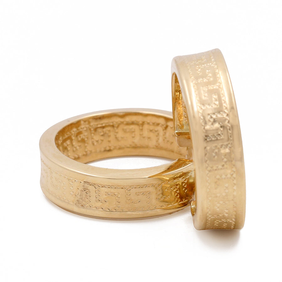 Two Miral Jewelry 14K yellow gold rings with intricate designs, one standing on its edge and the other lying flat, against a white background.