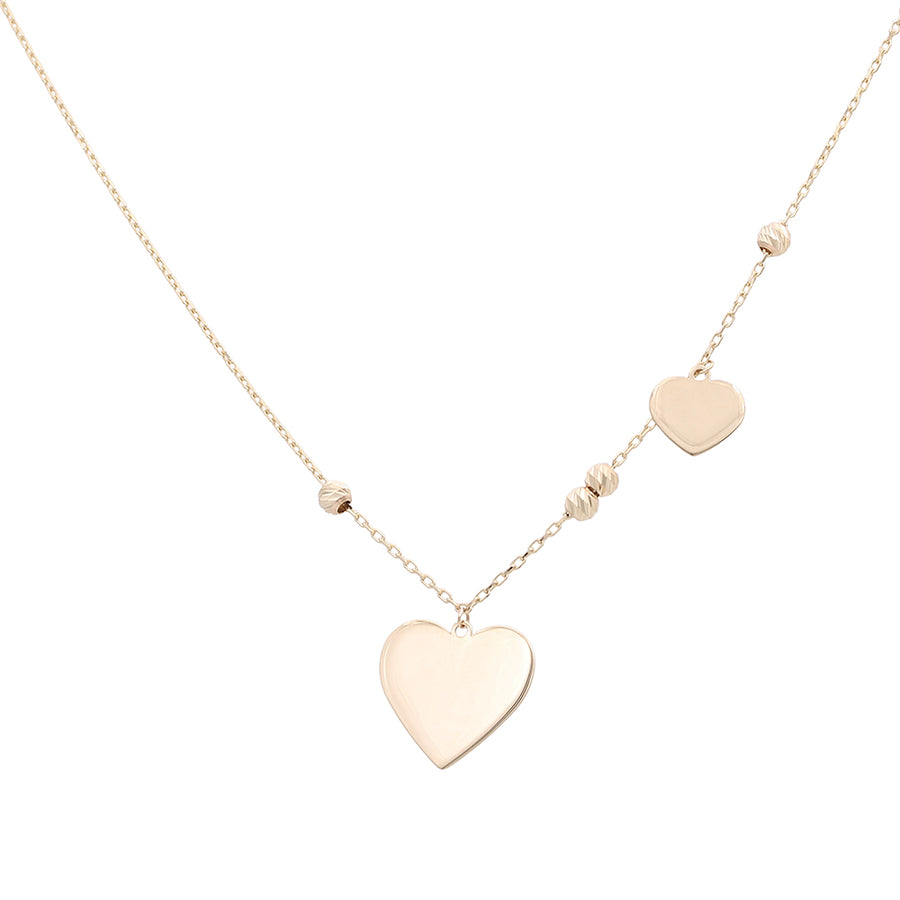 A Miral Jewelry 14K Yellow Hearts and Beads Hanging Necklace with two heart charms hanging.