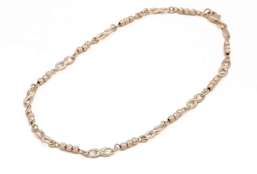 A 14K Yellow Gold Beads and Infinity Ankle Bracelet with a chain link from Miral Jewelry.