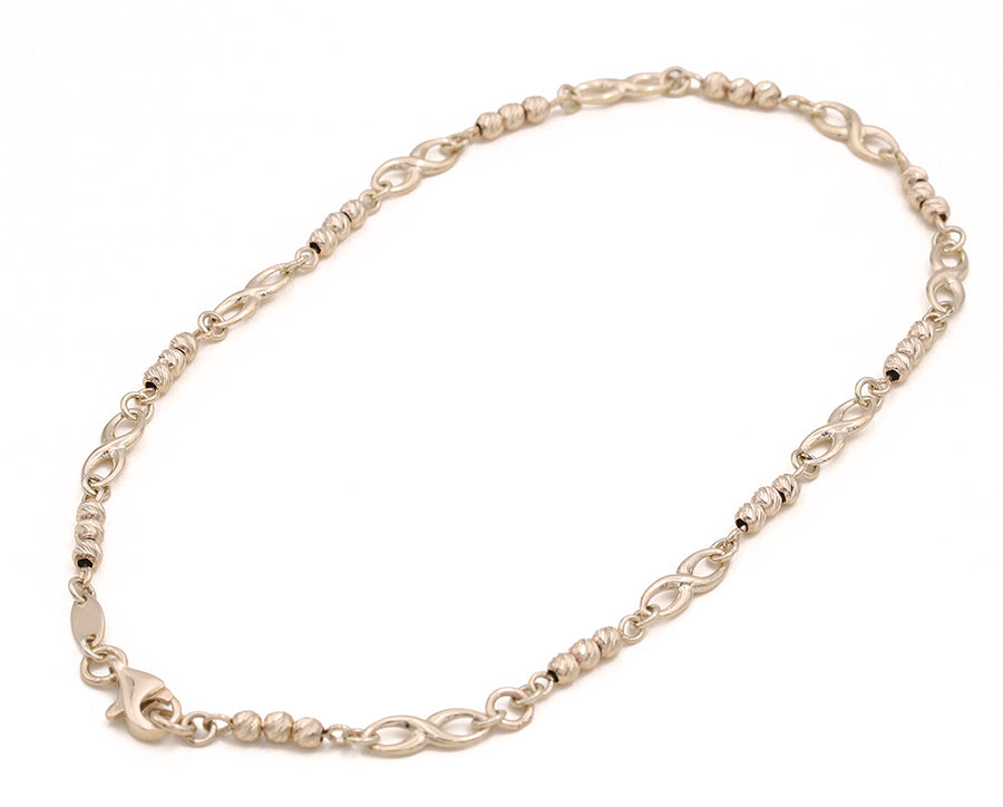 A Miral Jewelry 14K Yellow Gold Beads and Infinity Ankle Bracelet with a clasp on a white background.