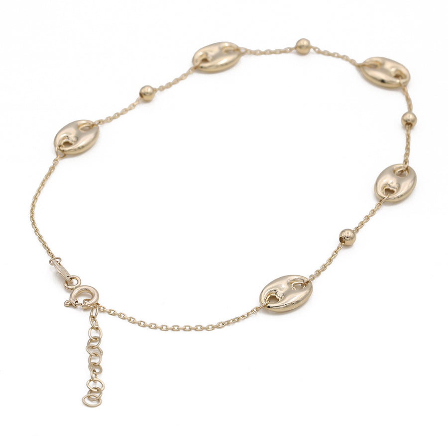 An ankle bracelet made of 14K yellow gold, adorned with a charm has been replaced by the given product name and brand name: The Miral Jewelry 14K Yellow Fashion Beads Ankle Bracelet, adorned with a charm.