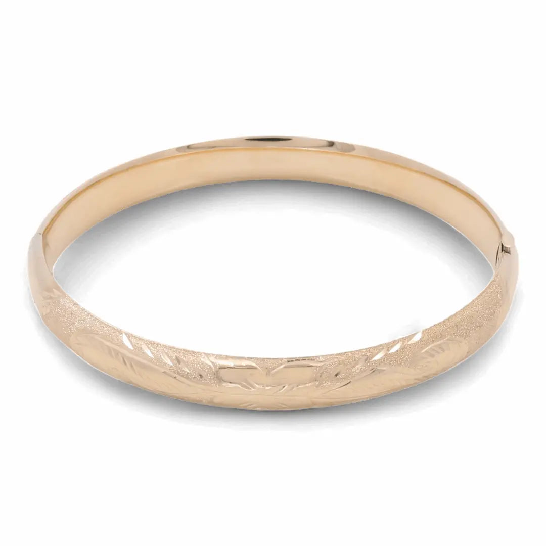 The 14K Yellow Gold Fashion Filigree Bangle by Miral Jewelry features a smooth surface and delicate filigree work around the circumference, making it a luxurious accessory that effortlessly enhances your elegant style.