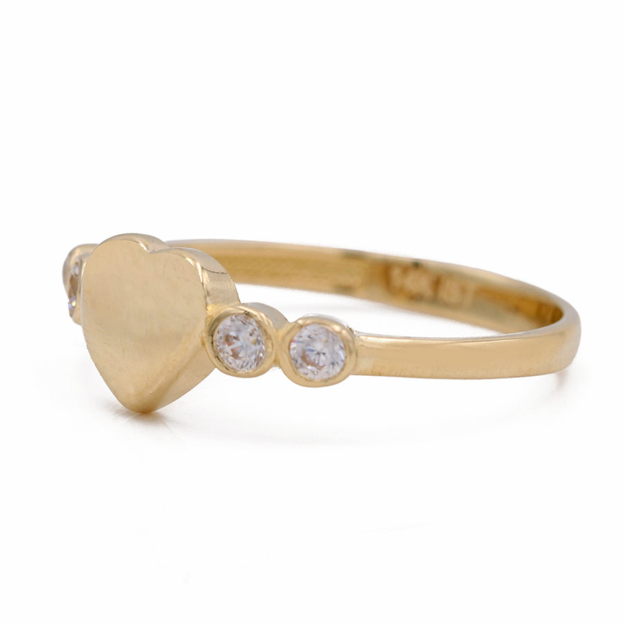A Miral Jewelry 14K yellow gold heart ring accented with three diamonds.