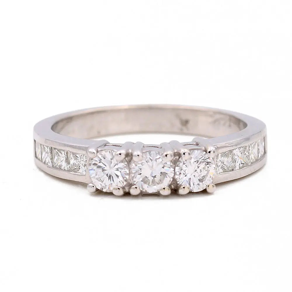 The Miral Jewelry White Gold 10k Ring for women features a trio of round diamonds at the center and square-shaped diamonds along the band.