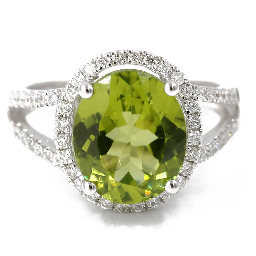 Introducing the White 14 Karat Fashion Ring Size 7 With 0.45Tw Round Diamonds And 4.88Tw Oval Peridots by Miral Jewelry: a stunning piece featuring a large oval green gemstone surrounded by small round diamonds on a double band encrusted with additional white diamonds.