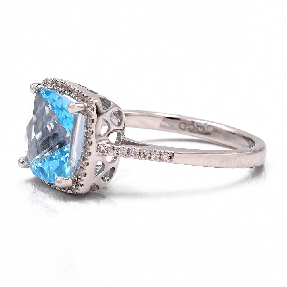 A Women's white 14 karat silver Contemporary Ring by Miral Jewelry, featuring a large, square-cut blue topaz, with small round diamonds adorning the band.