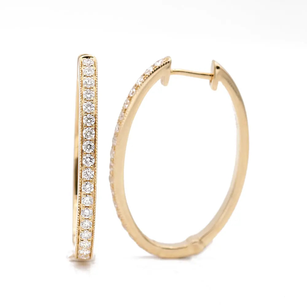 Miral Jewelry Oval Hoop Earrings With 0.65Tw Round Diamonds with a row of small, round diamonds embedded on the front surface. One earring is shown in a closed position, and the other is open. White background. Perfect for women's jewelry collections.
