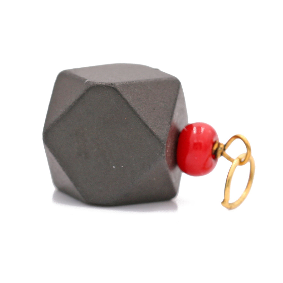 A black and red geometric shape with a 14k Yellow Gold Azabache Pendant by Miral Jewelry for added protection.