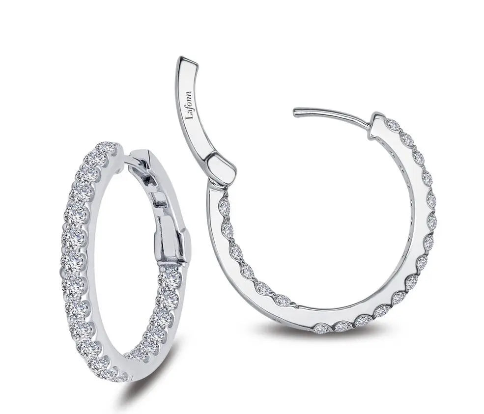 Introducing the Miral Jewelry Hoop Earrings, a stunning pair of sterling silver inside-out hoops adorned with simulated diamonds. One earring is fully closed, showcasing a continuous row of shimmering stones, while the other is half-open, revealing an intricate latch mechanism.